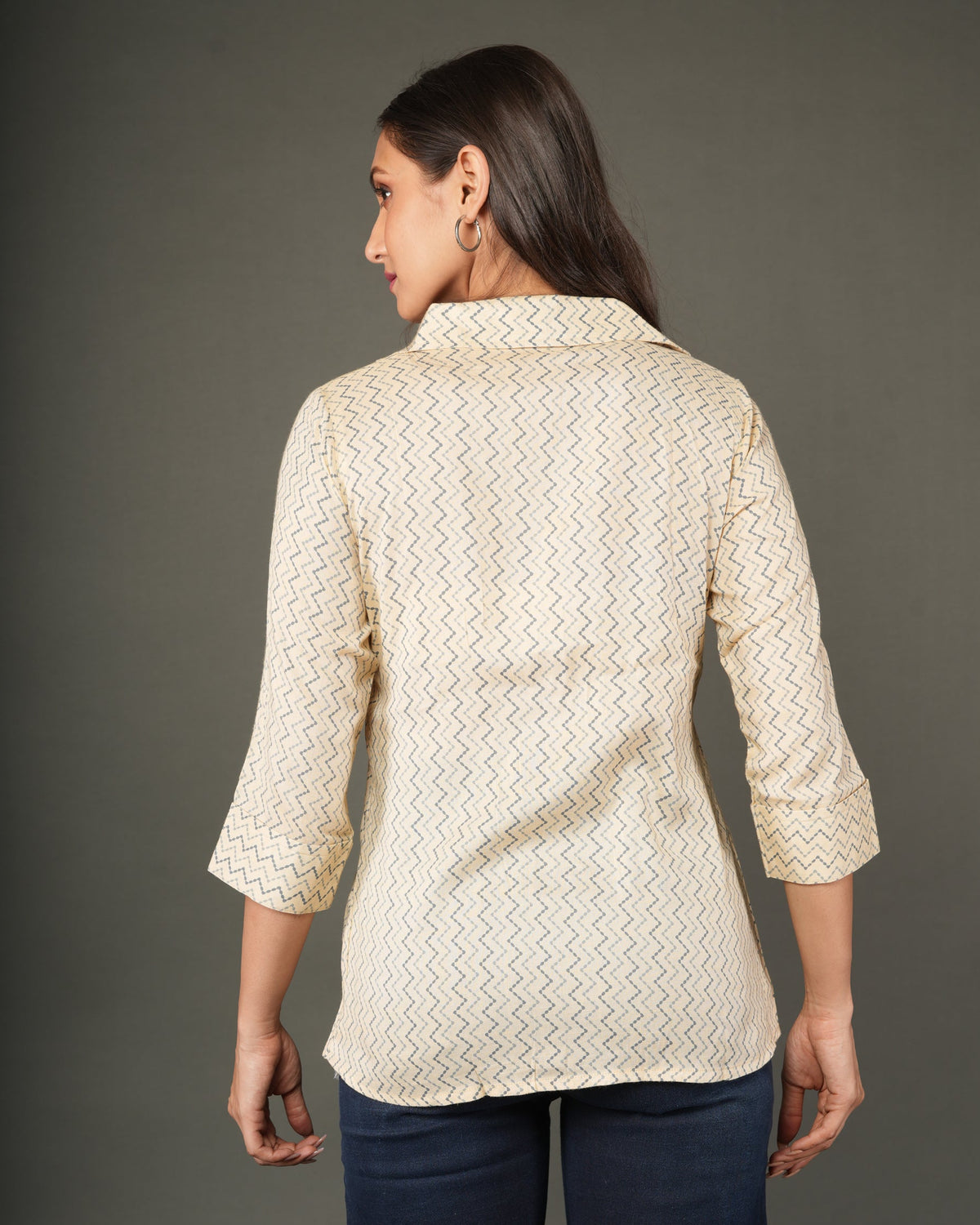 A woman modeling a beige and white zigzag patterned button-up shirt with dark brown buttons