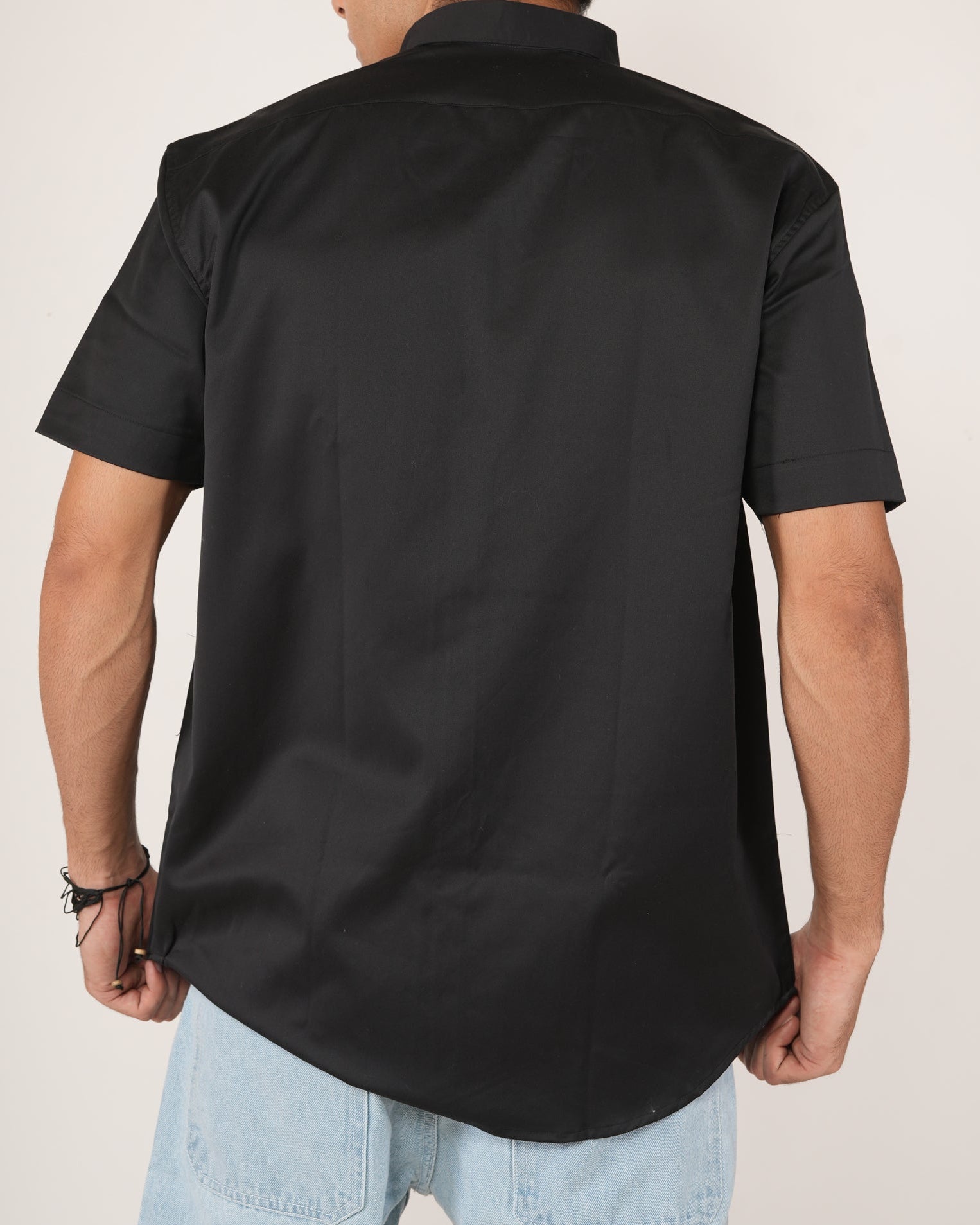 Man wearing a black half-sleeve shirt and light blue jeans.