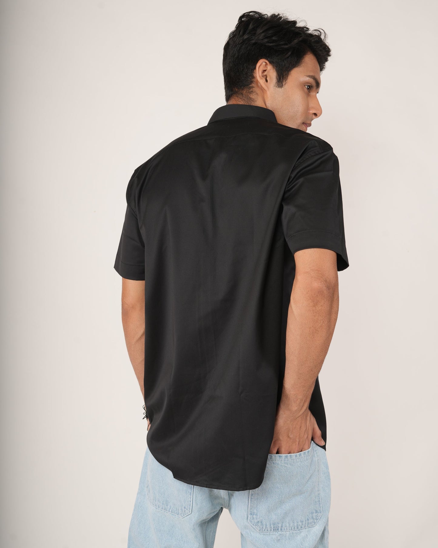 Man wearing a black half-sleeve shirt and light le jeans.