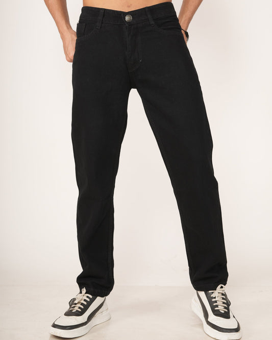 Man wearing black jeans and black and white sneakers.