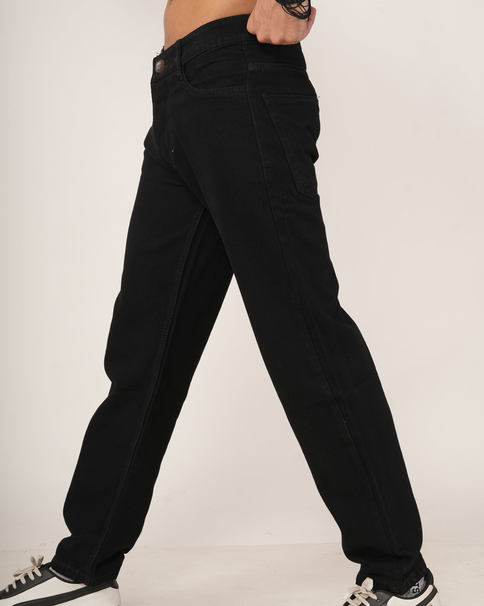 Person wearing black relaxed fit jeans and black and white sneakers.