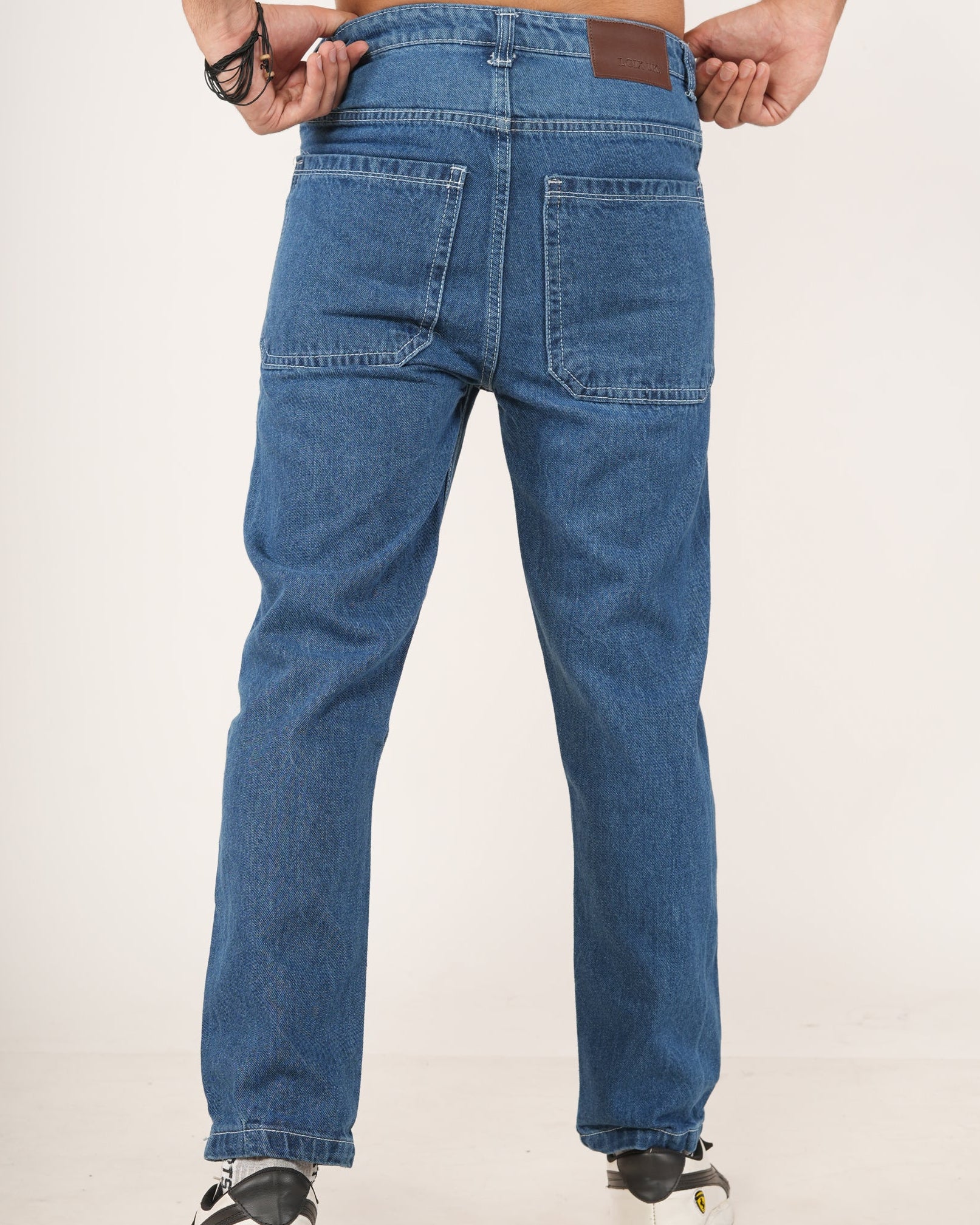 Rear view of a man wearing blue denim jeans with white sneakers.