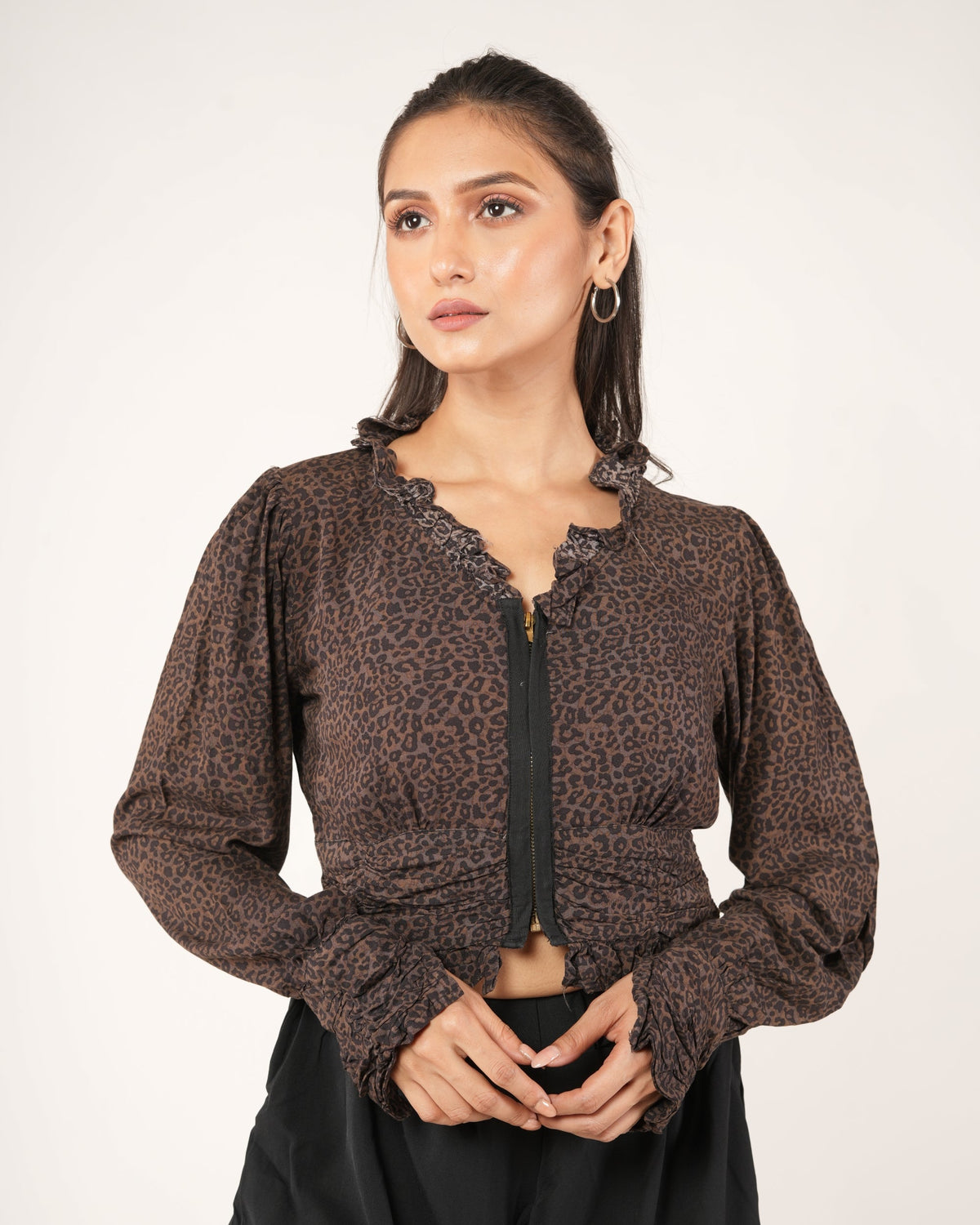 A woman modeling a brown leopard-print long-sleeve cropped top with a black front zipper