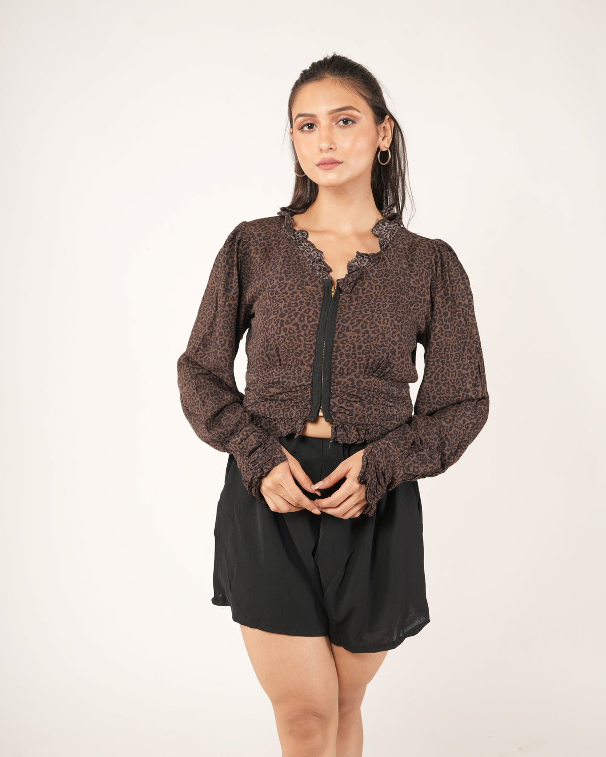 A woman modeling a brown leopard-print long-sleeve cropped top with a black front zipper