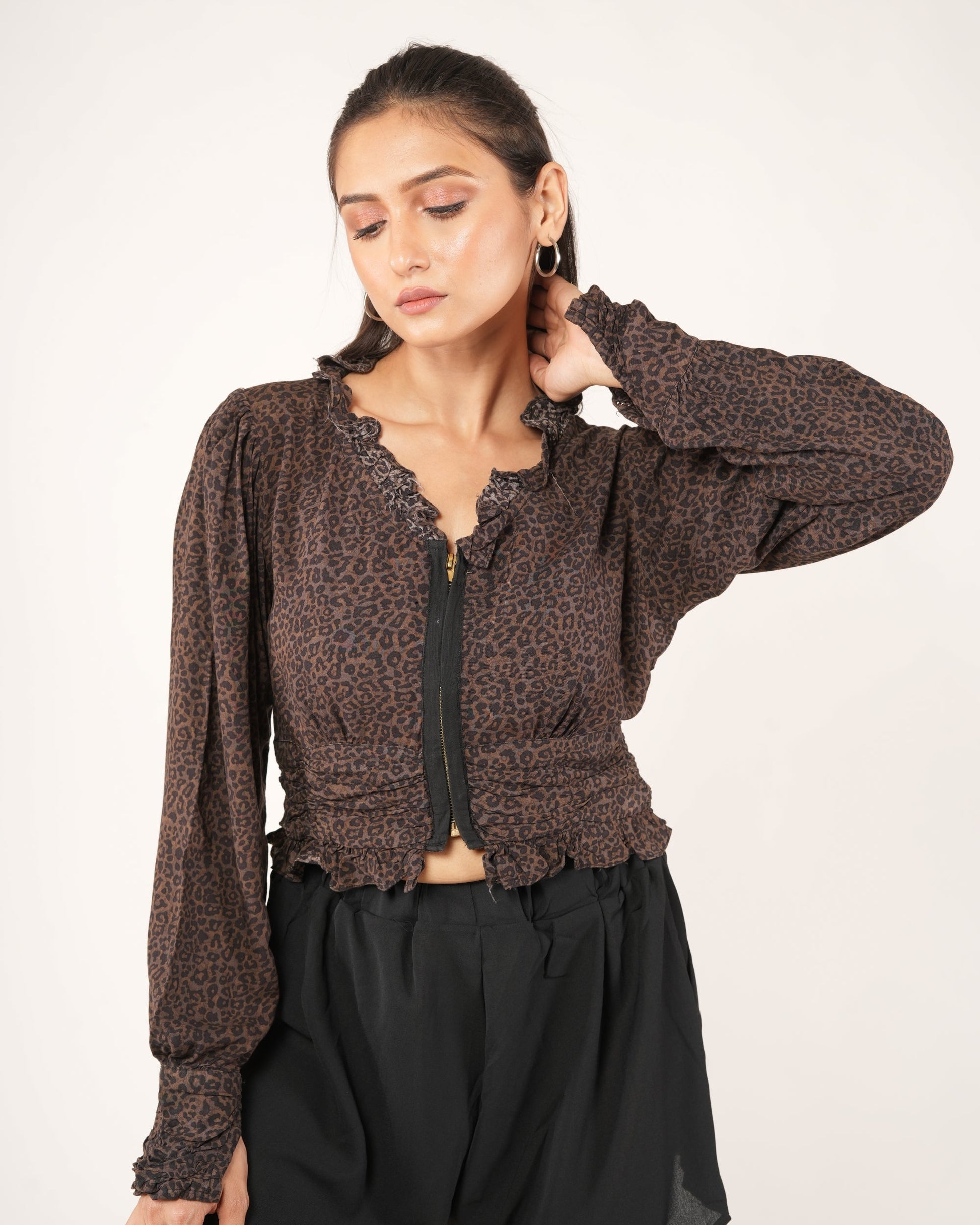 A woman modeling a brown leopard-print long-sleeve cropped top with a black front zipper