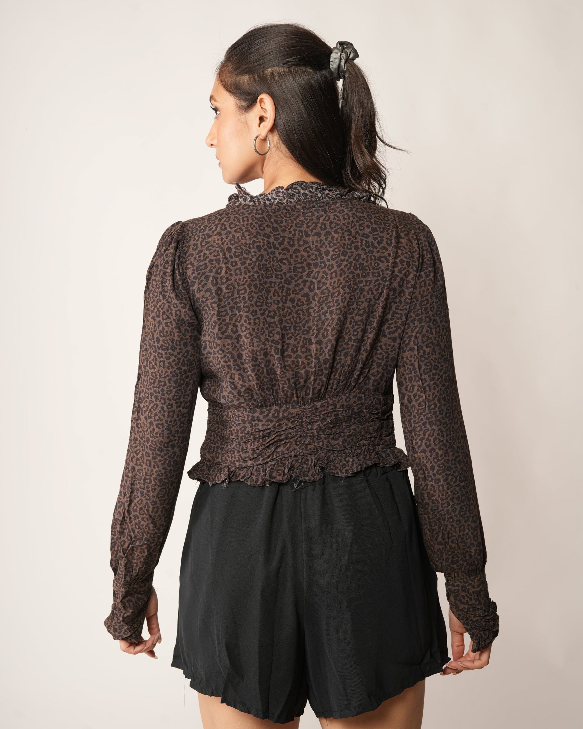 A woman modeling a brown leopard-print long-sleeve cropped top with a black front zipper