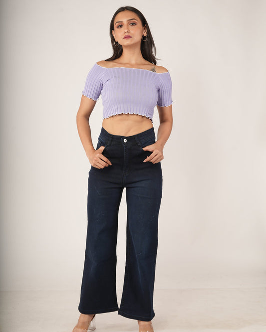 A woman modeling a light purple off-the-shoulder short-sleeve crop top paired with dark blue wide-leg jeans,.