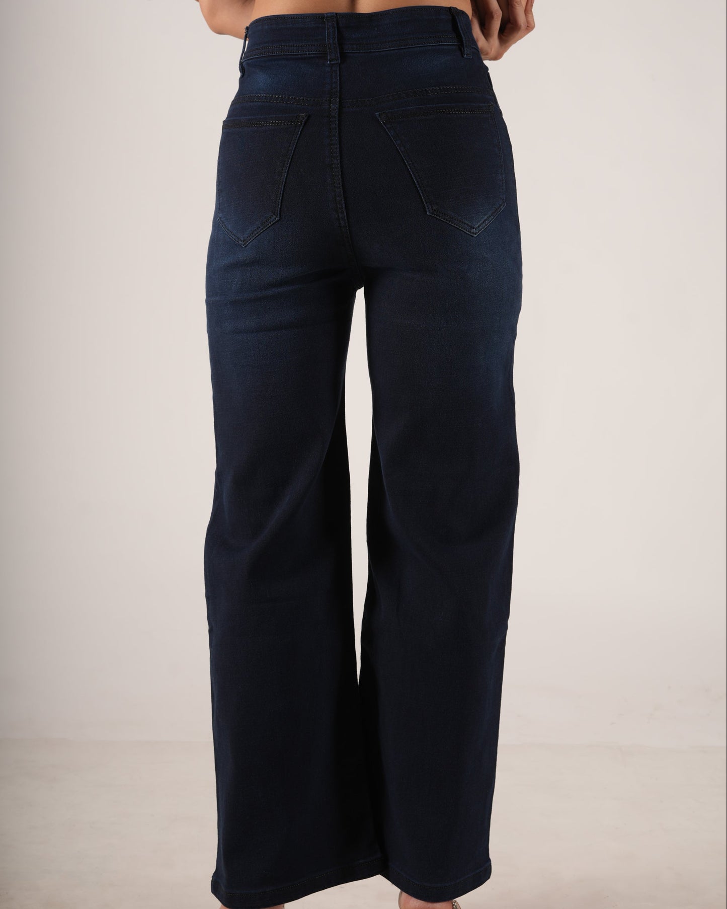 A person shown from the back wearing dark navy wide-leg jeans and a light purple ribbed crop to.