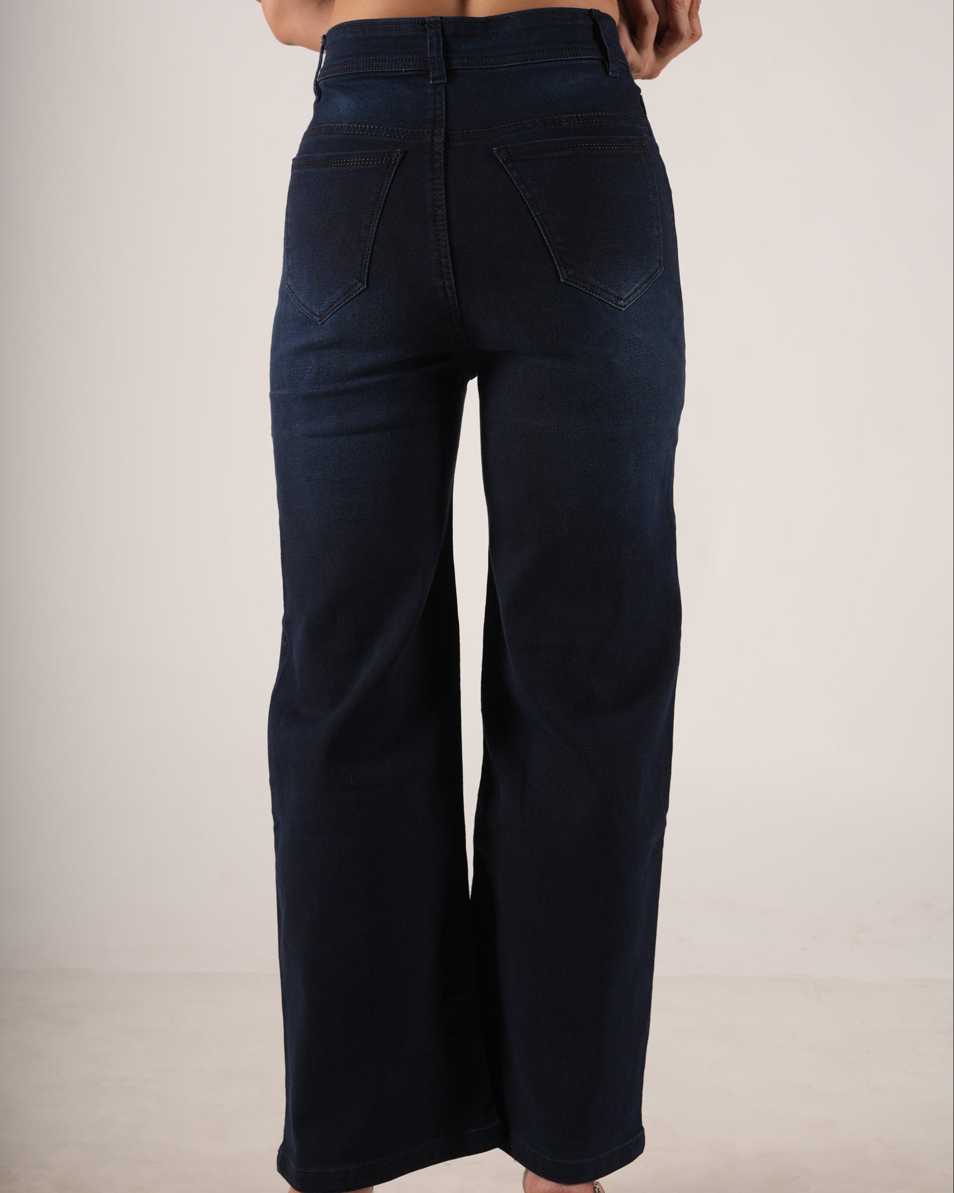 A person shown from the back wearing dark navy wide-leg jeans and a light purple ribbed crop to.
