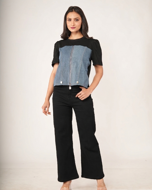 Woman wearing a black and blue top with black pants on a plain background
