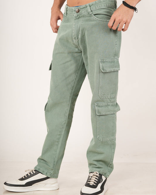A man wearing sage green 8 pocket cargo jeans with side flap pockets and black-and-white sneakers.