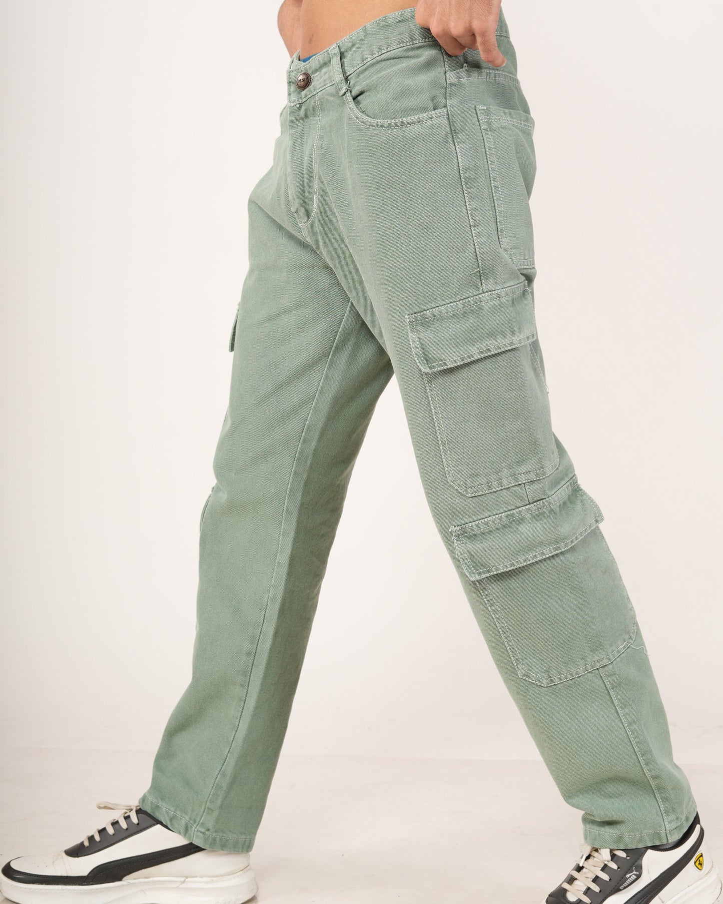 A side-profile view of a model wearing sage green 8 pocket cargo jeans, styled with black and white sneakers.
