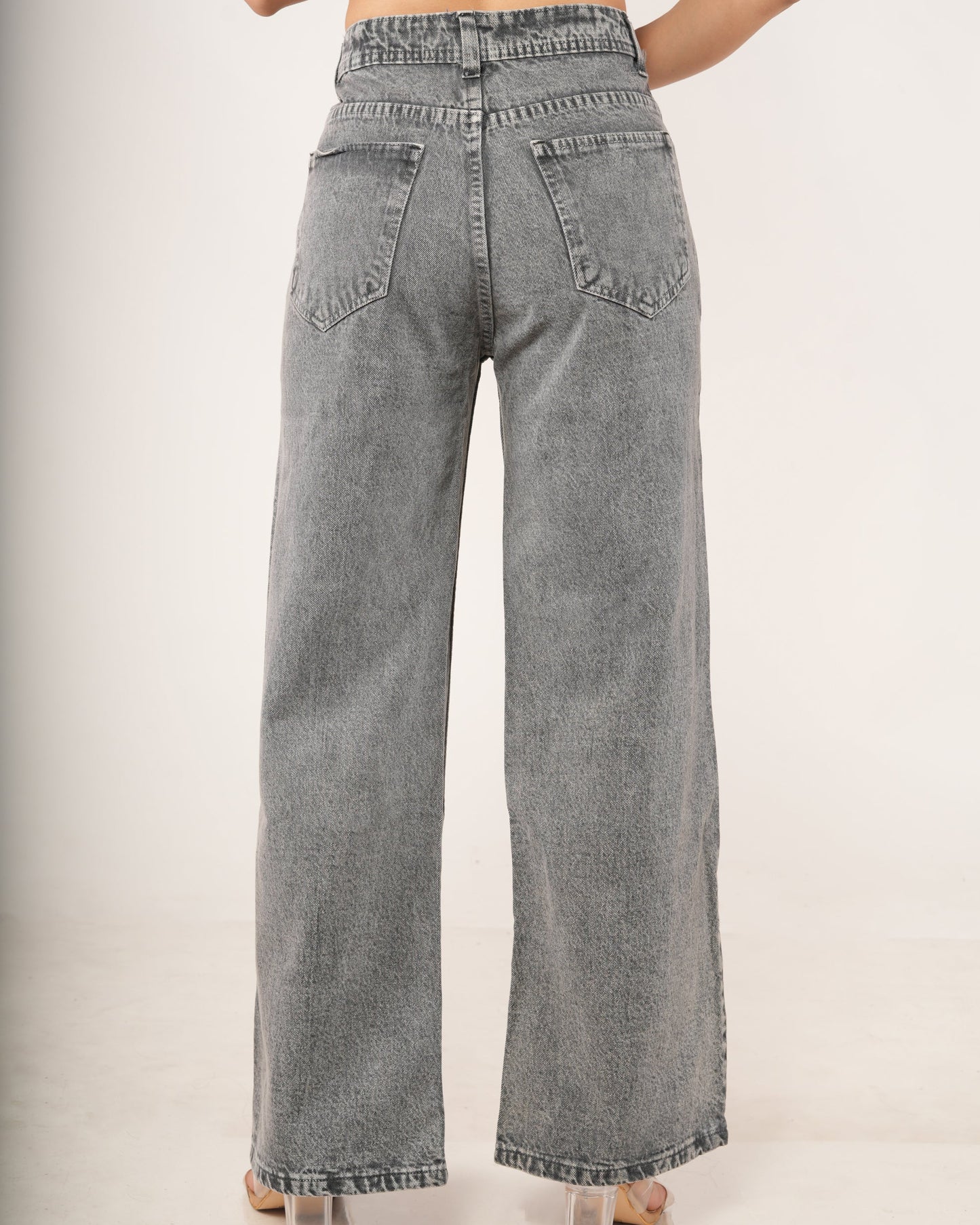 A person shown from the back wearing high-waisted, wide-leg gray denim jeans with a faded wash.