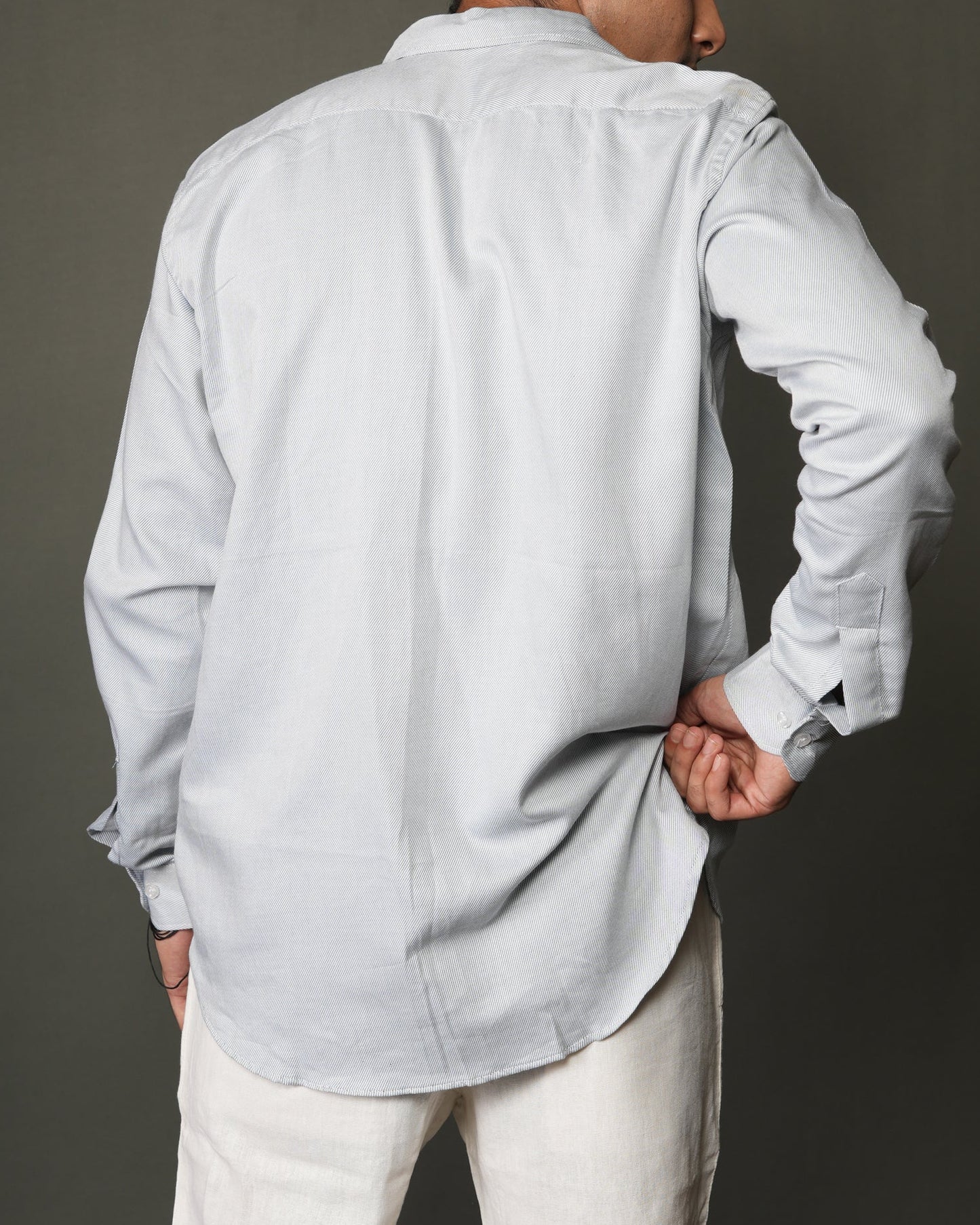 Person wearing a ice blue button-up shirt and white pants.