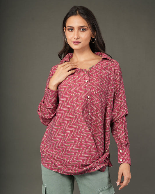 A woman modeling a long-sleeve, button-front top with a pink and red chevron pattern.