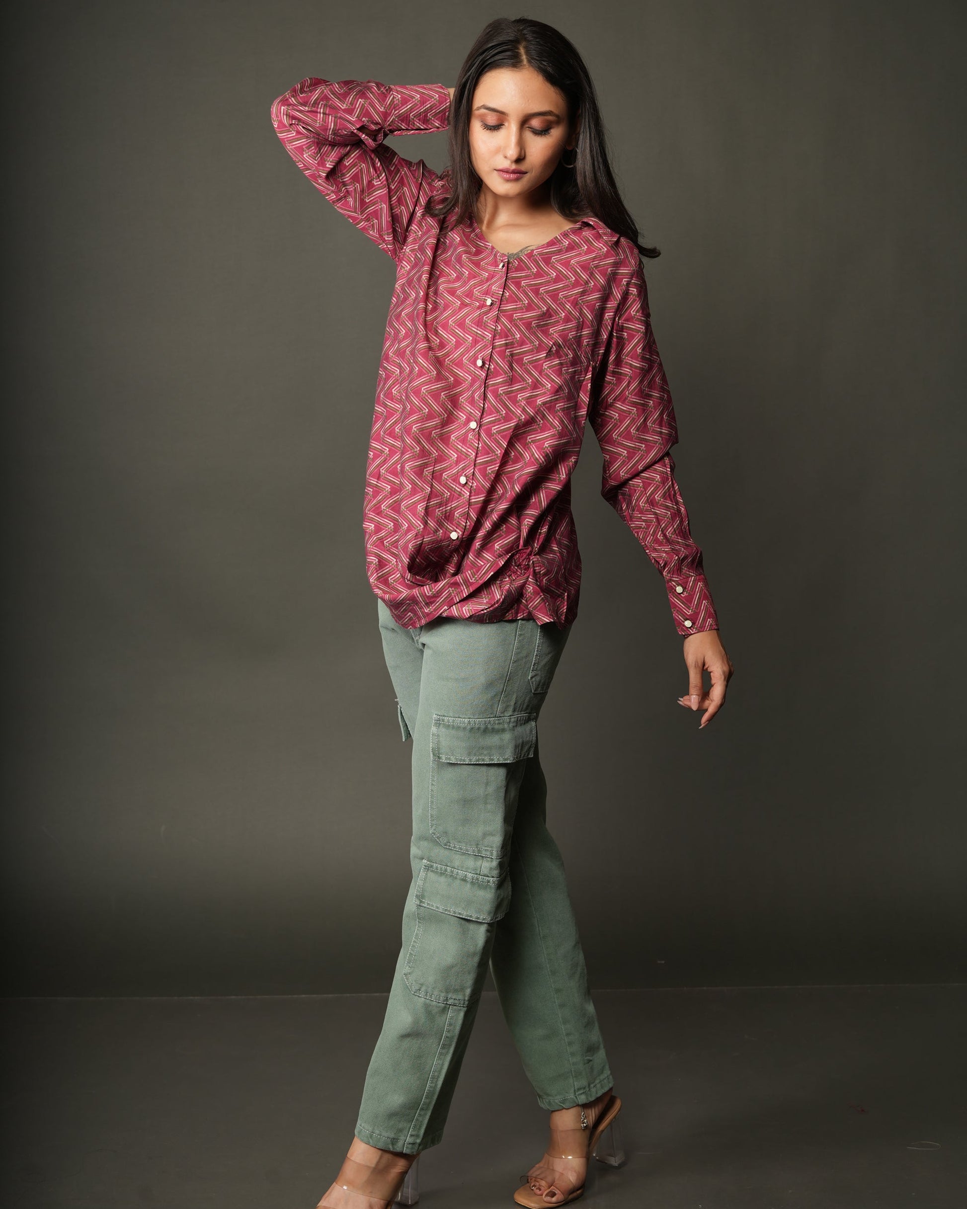 A woman modeling a long-sleeve, button-front top with a pink and red chevron pattern.