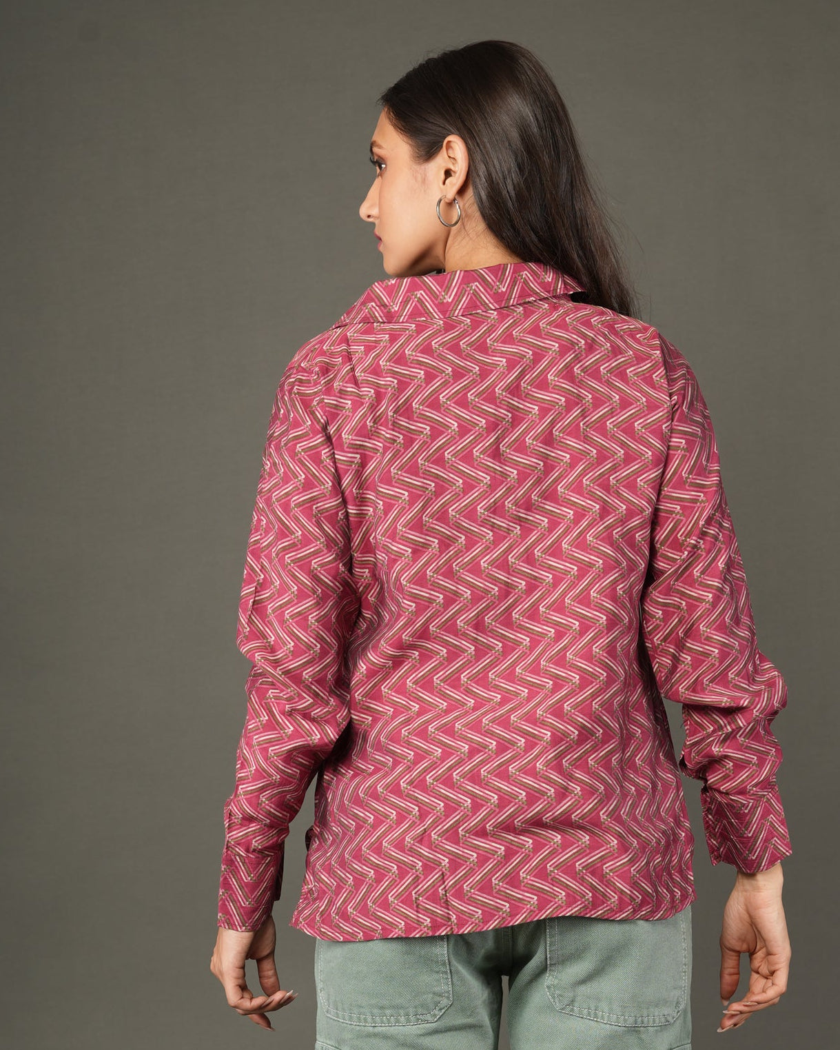 A woman modeling a long-sleeve, button-front top with a pink and red chevron pattern.