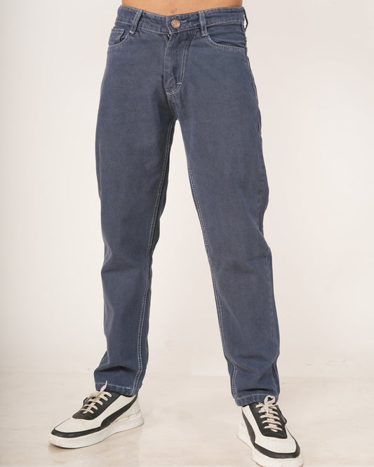 A person modeling a pair of slate blue straight-fit jeans with black and white sneakers.