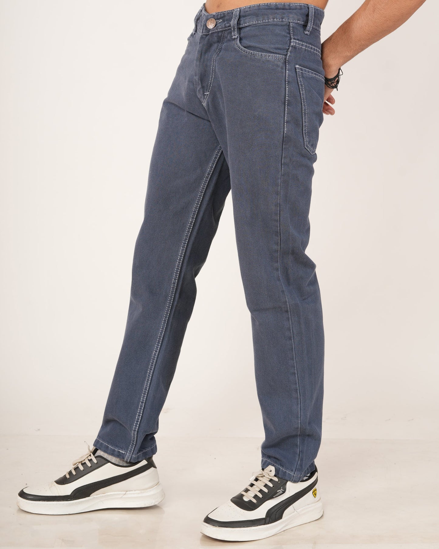 A man wearing slate blue straight-fit jeans and white sneakers.