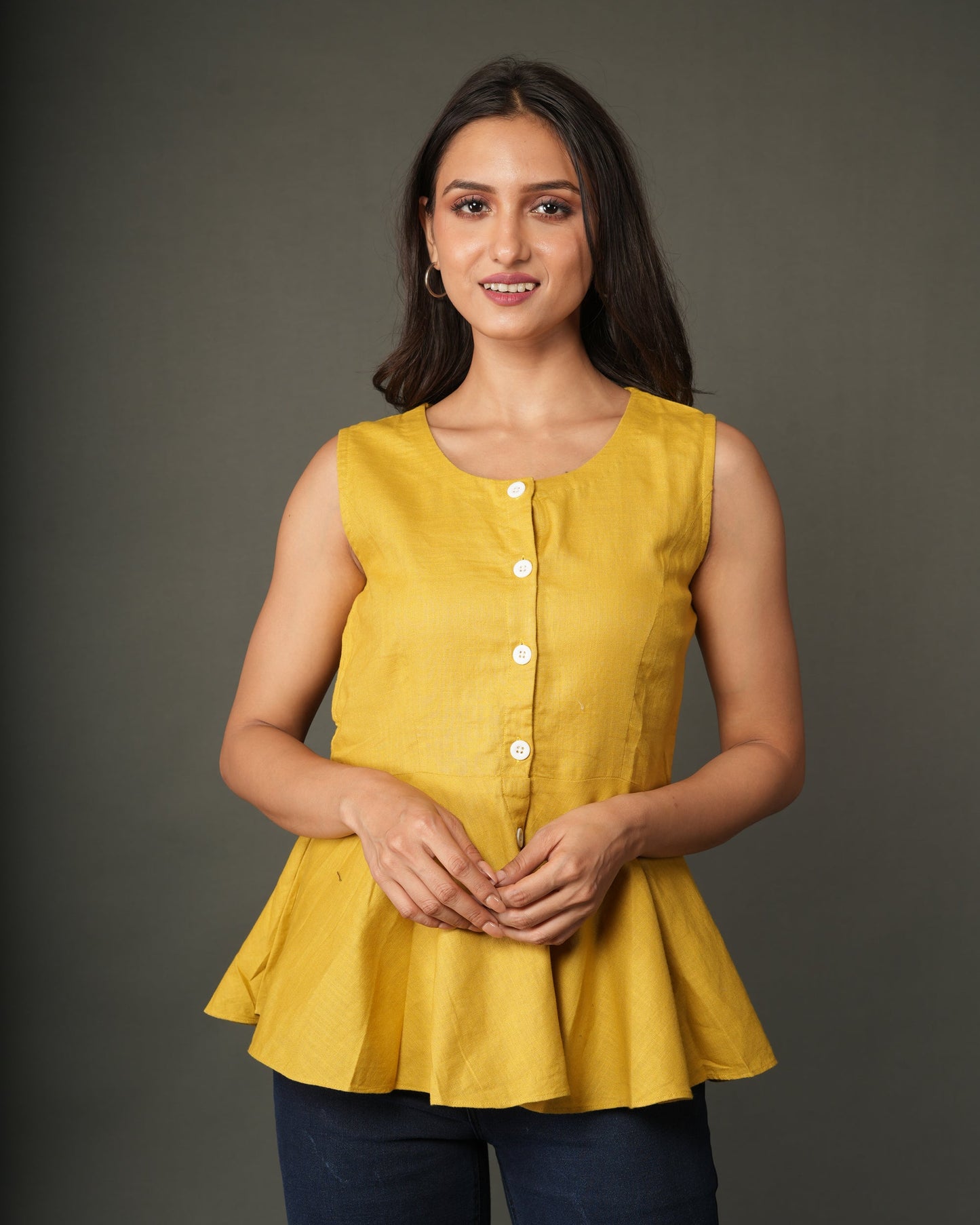 A woman modeling a sleeveless mustard yellow linen-blend peplum top