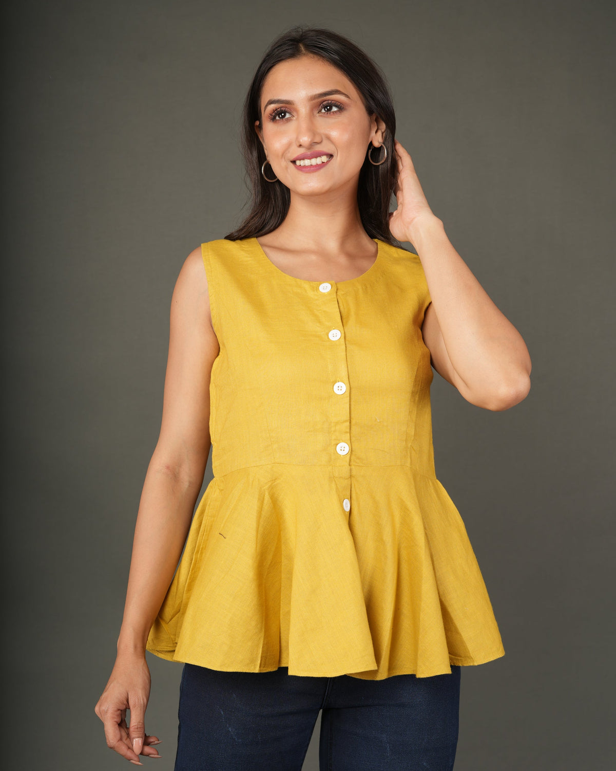A woman modeling a sleeveless mustard yellow linen-blend peplum top