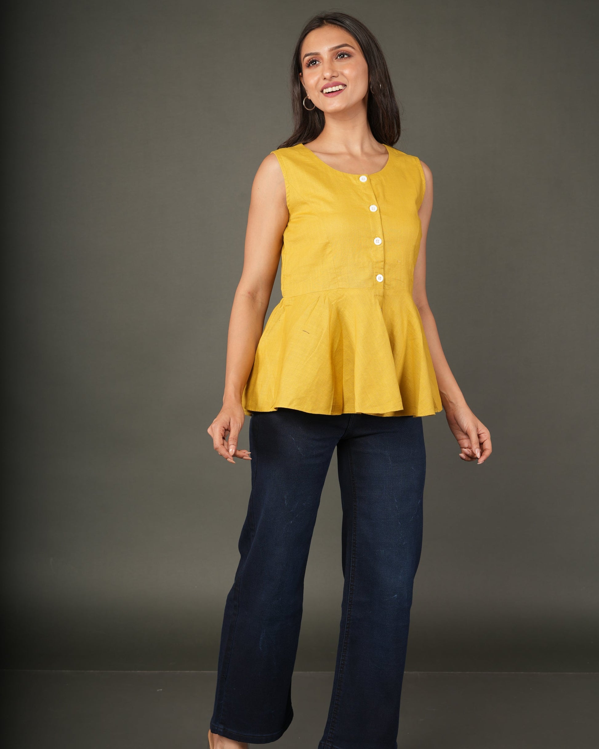 A woman modeling a sleeveless mustard yellow linen-blend peplum top