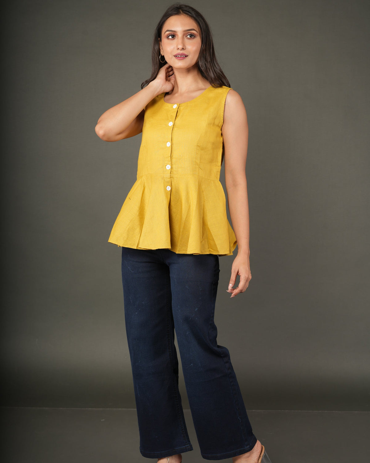 A woman modeling a sleeveless mustard yellow linen-blend peplum top