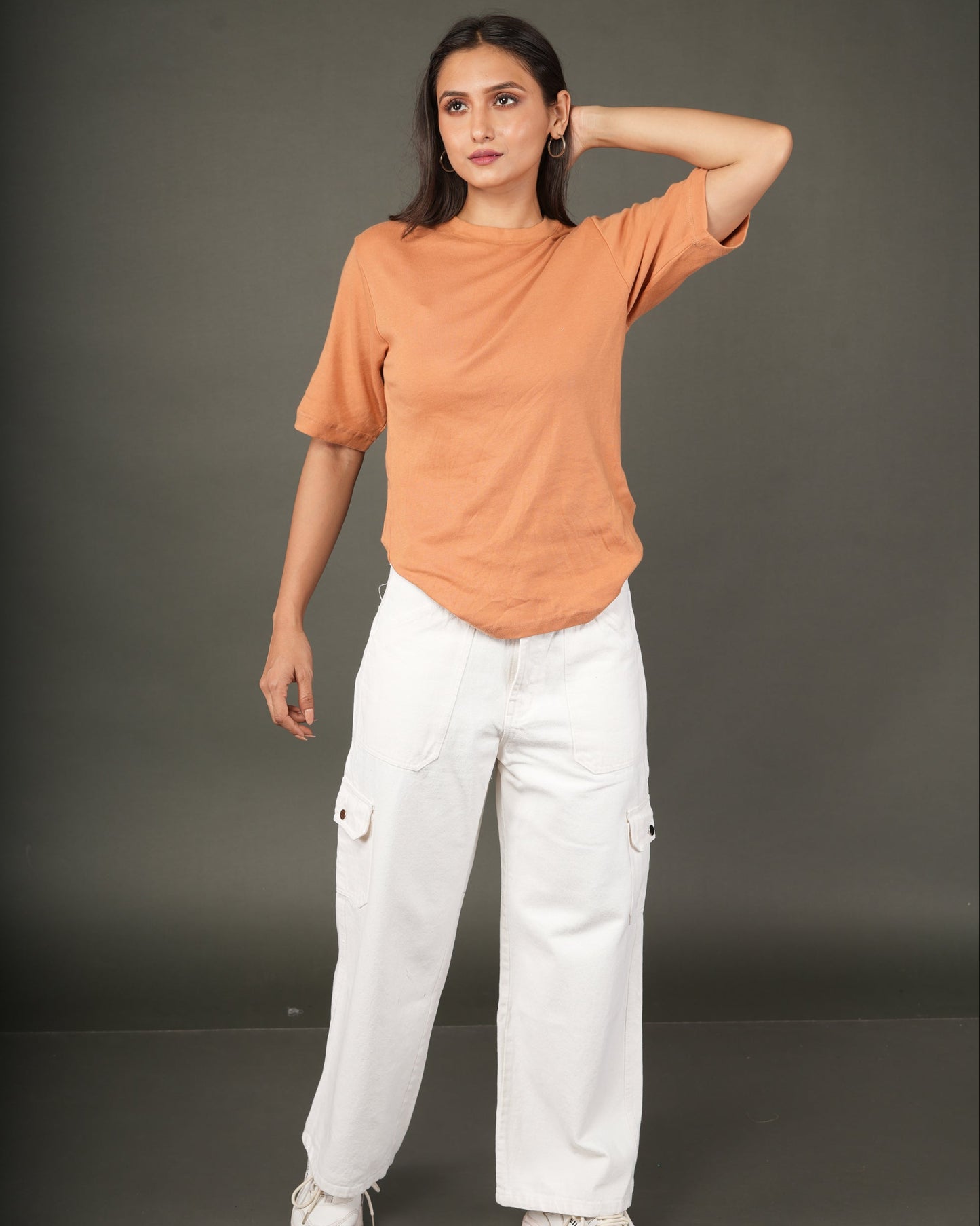 Woman wearing an orange top and white pants.