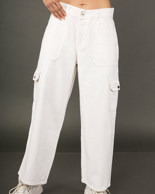 A person wearing loose white cargo pants with flap side pockets, paired with a cropped orange top and white sneakers..