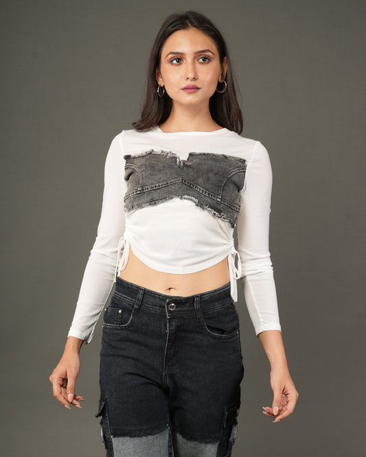 A woman modeling a white long-sleeve crop top with a distressed dark gray denim chest panel
