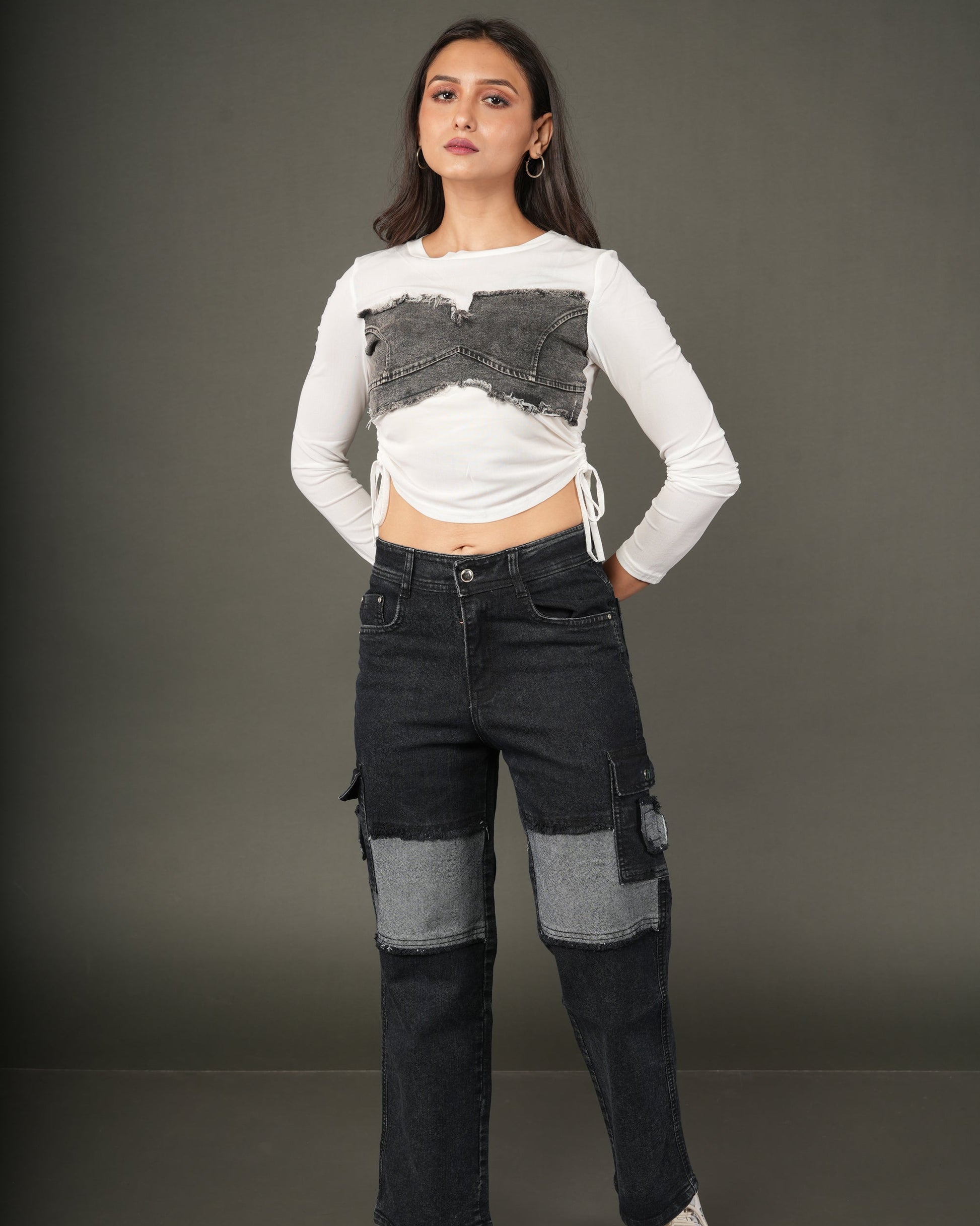 A woman modeling a white long-sleeve crop top with a distressed dark gray denim chest panel