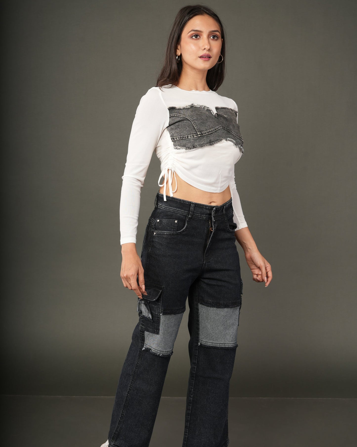 A woman modeling a white long-sleeve crop top with a distressed dark gray denim chest panel