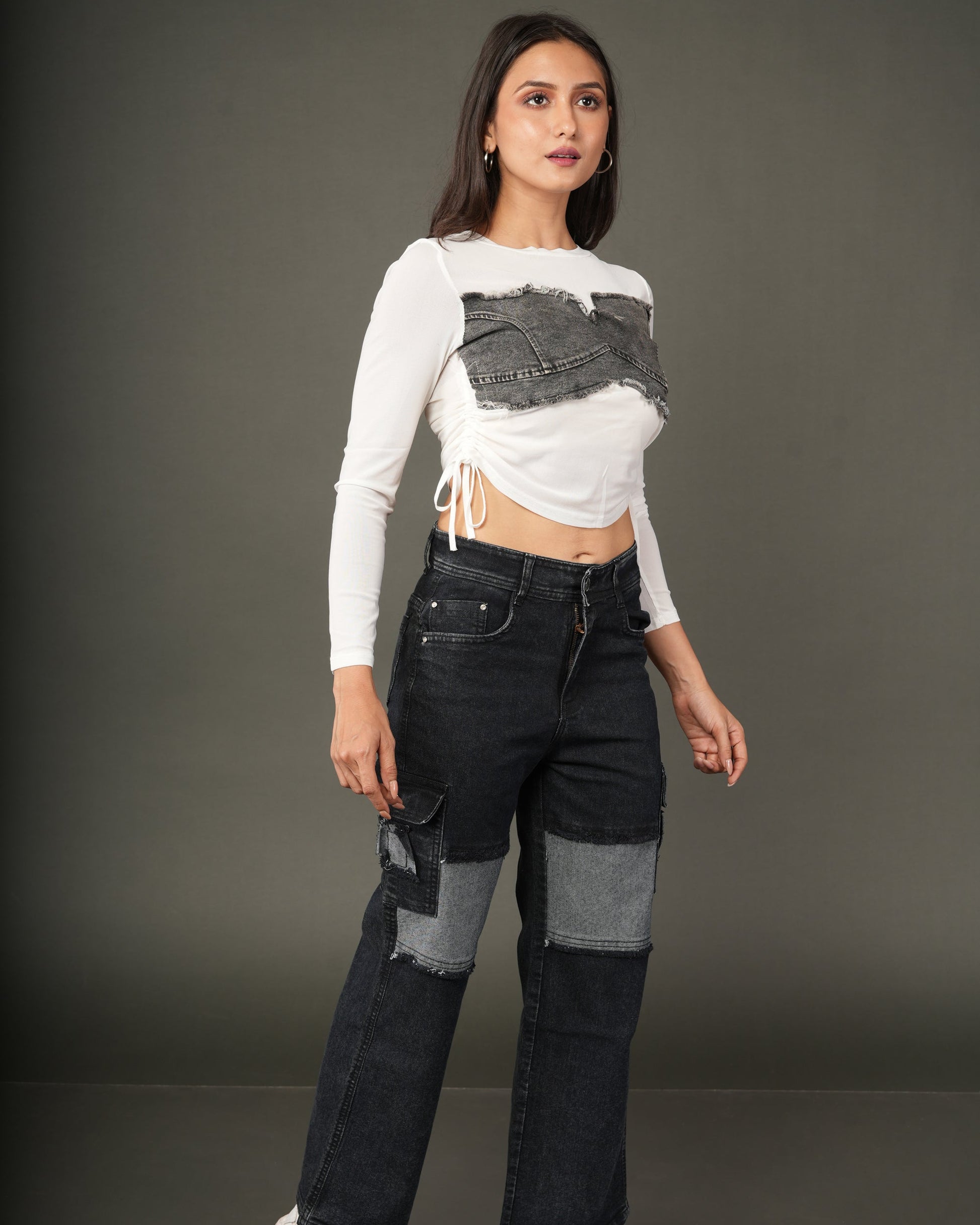 A woman modeling a white long-sleeve crop top with a distressed dark gray denim chest panel