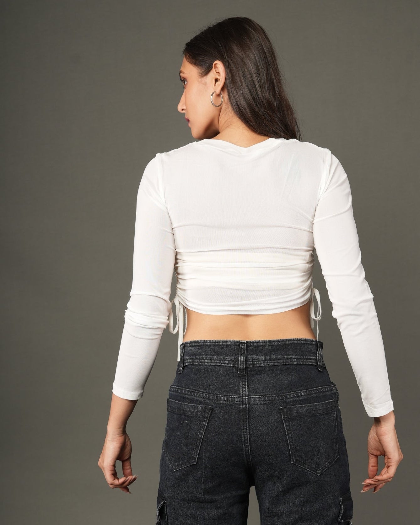 A woman modeling a white long-sleeve crop top with a distressed dark gray denim chest panel