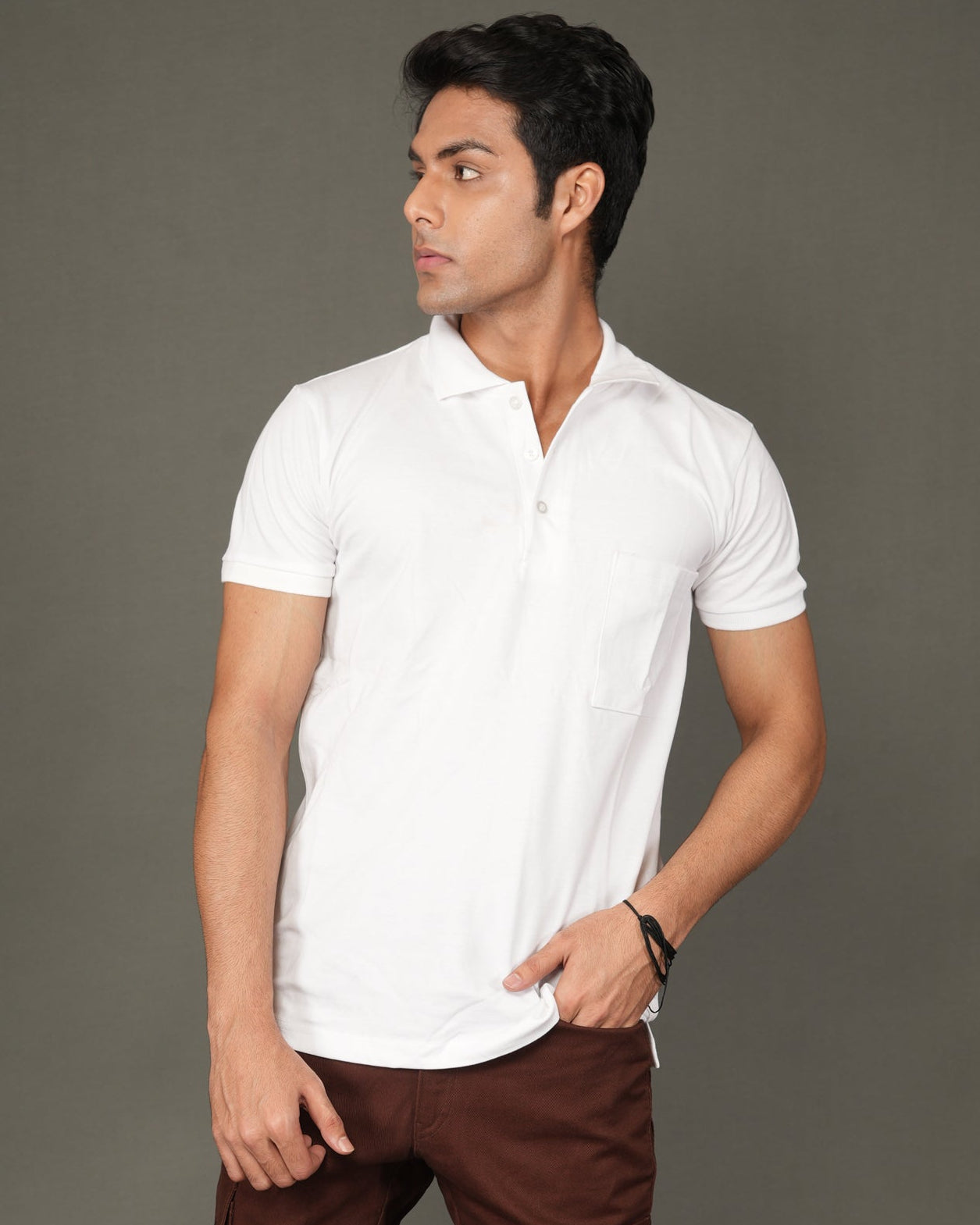 Man wearing a white polo t-shirt and brown pants against a gray background