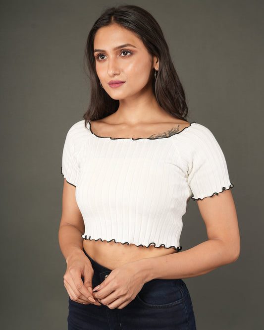 A woman modeling a white short-sleeve ribbed crop top with a scalloped black trim, paired with dark blue jeans.